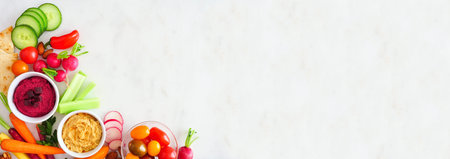 Mixed fresh vegetables and hummus, top view corner border on a white marble background