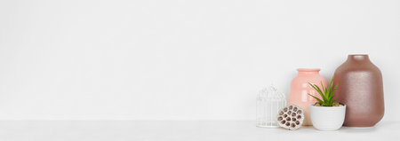 Vase and succulent plant home decor against a white shelf and wall banner with copy space