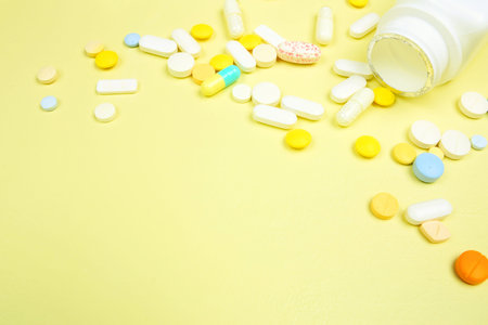 Medicine corner border with white bottle and spilling pills on a yellow