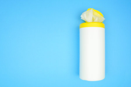 Container of alcohol sanitizing wipes, top view over a blue