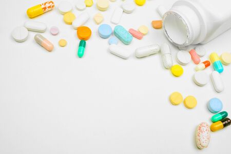 Medicine corner border with white bottle and spilling pills on a white backgroundの写真素材