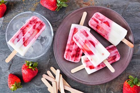 Strawberry vanilla yogurt ice pops, top down scene on dark stoneの写真素材