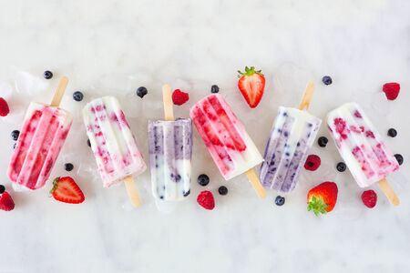 Assorted berry fruit yogurt ice cream, top view in a row over marbleの写真素材