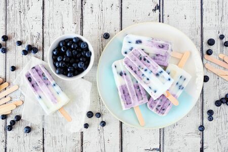 Blueberry yogurt ice pops, top down table scene over white woodの写真素材