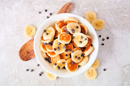 Pancake cereal with bananas and chocolate chips, top view over white marbleの写真素材