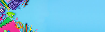 School supplies corner border. Top down view over a blue paper banner background with copy space....