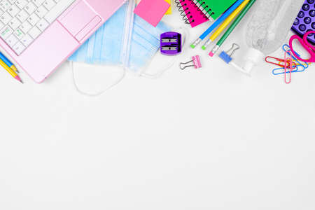 School or office supplies and coronavirus prevention items. Overhead view top border on a white background.の写真素材