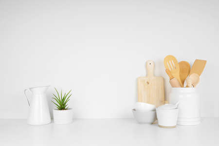 Kitchenware and utensils on a white shelf or countertop with a white wall background and copy space. Home kitchen cooking decor.の写真素材