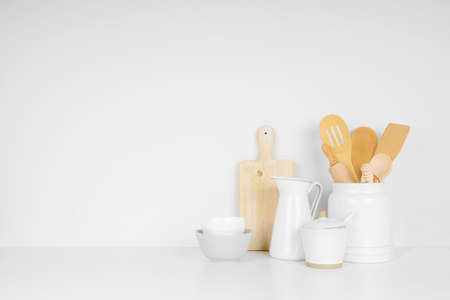 Kitchenware and utensils on a white shelf or counter against a white wall background with copy space. Home kitchen cooking decor.の写真素材