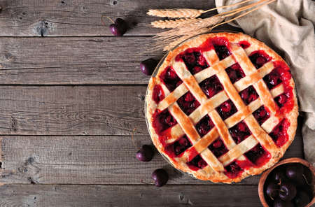 Cherry pie table scene against a rustic wood background with copy space. Autumn food concept.の写真素材