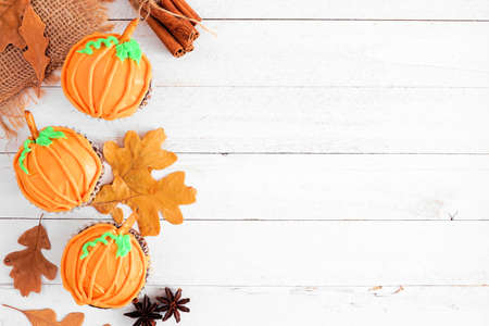 Autumn pumpkin cupcakes. Top view side border on a white wood background with copy space.の写真素材