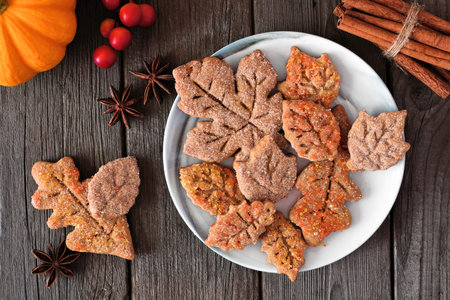 Plate of autumn leaf cookies. Top view table scene on a rustic wood background.