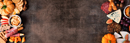 Fall charcuterie double border against a dark stone banner background. Assortment of cheese and meat appetizers. Copy space.の写真素材