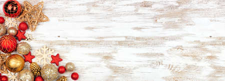 Christmas corner border of red and gold ornaments. Above view on a white rustic white wood banner background. Copy space.の写真素材