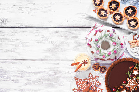 Selection of Christmas holiday desserts and sweets. Overhead view side border over a white wood...