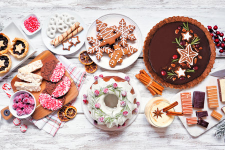Variety of Christmas holiday desserts and sweets. Above view table scene over a white wood...