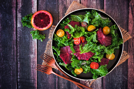 Healthy salad with kale and red blood oranges. Above view table scene against a rustic wood background.の写真素材