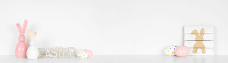 Easter decor on a white shelf. Rustic wood signs, eggs and modern glass bunnies against a white wall...