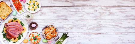 Traditional Easter ham dinner. Overhead view corner border on a white wood banner background with...