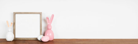 Mock up wooden frame with Easter Eggs and modern glass bunny decor on a wood shelf. Square frame...