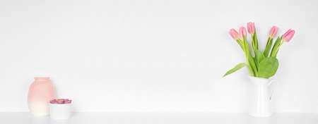 Home decor on a shelf. Vases, tulip flowers and succulent plant. White shelf against a white wall. Banner with copy space.の写真素材