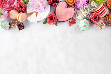 Mother's Day charcuterie top border against a white marble background. Variety of cheese, meat, fruit and sweet appetizers. Copy space.の写真素材