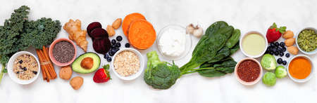 Set of healthy food ingredients. Top view table scene on a white marble banner background. Super food concept with green vegetables, berries, whole grains, seeds, spices and nutritious items.の写真素材