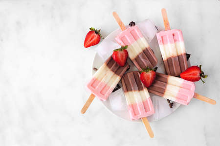 Group of neapolitan yogurt popsicles on a plate.の写真素材