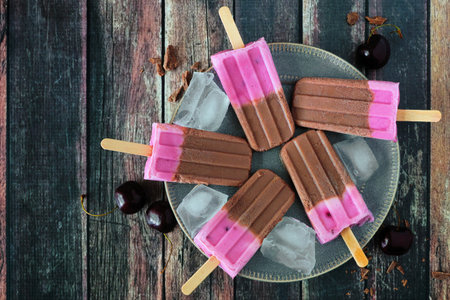 Plate of chocolate and cherry popsicles.の写真素材