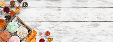 Summer ice cream bar with assorted ice cream flavors and tasty toppings. Top view corner border over...