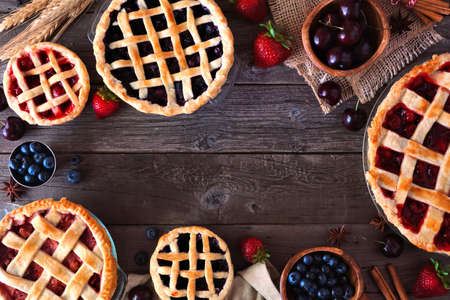 Frame of a variety of homemade fruit pies. Top view over a rustic wood background. Autumn food concept. Copy space.の写真素材