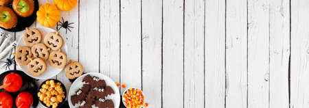 Rustic Halloween treat corner border over a white wood banner background with copy space. Overhead view. Selection of candied apples, cookies, candy and sweets.の写真素材