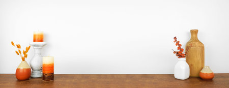 Autumn decor on a wood shelf against a white wall background. Banner with copy space. Candles, vases...