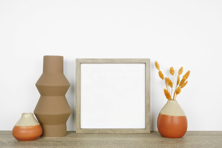 Mock up wood frame with fall vases and home decor on a wooden shelf. Autumn concept. Square frame...