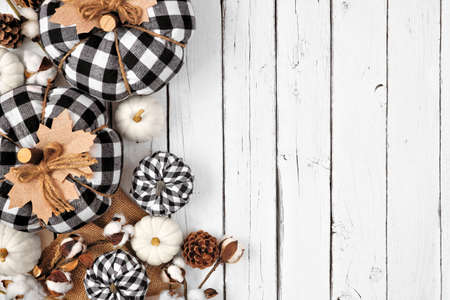 Modern farmhouse autumn side border over a white wood background. Black and white buffalo plaid pumpkins and rustic decor. Top view with copy space.の写真素材