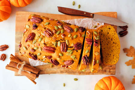 Fall pumpkin bread sliced. Overhead view table scene on a white marble background.の写真素材
