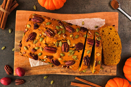 Autumn pumpkin bread sliced. Above view table scene over a dark background.