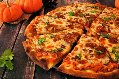 Autumn pizza with pumpkin sauce, gouda and caramelized onions. Close up side view with a dark wood background.の写真素材
