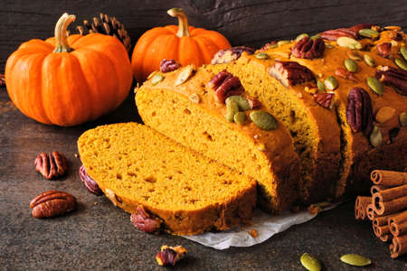 Autumn pumpkin bread. Slices close up against a dark table scene background.の写真素材
