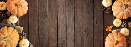 Cozy autumn double border on a rustic dark wood banner background. Above view. Blanket, pumpkins and natural decor. Copy space.の写真素材