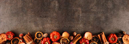 Autumn baking spices and ingredients. Bottom border on a dark stone banner background with copy space. Top down view.の写真素材