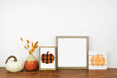 Autumn mock up. Wood frame,  wooden signs, pumpkins and fall branches on a wood shelf against a white wall. Modern farmhouse concept. Copy space.の写真素材