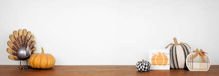 Thanksgiving decor on a wood shelf against a white wall banner background. Rustic turkey, and pumpkin decorations. Modern farmhouse decor. Copy space.の写真素材