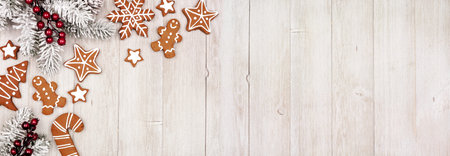 Christmas corner border of gingerbread cookies and frosty tree branches. Above view on a rustic grey...