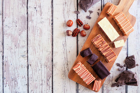 Fudge selection top down view on a wood serving board against a rustic white wooden background. Copy...