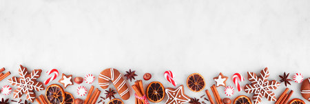 Christmas baking bottom border with cookies, peppermints and spices. Top view over a white marble background with copy space. Holiday baking concept.の写真素材