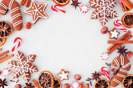 Christmas baking frame with cookies, peppermints and spices. Above view over a white marble background with copy space. Holiday baking concept.の写真素材