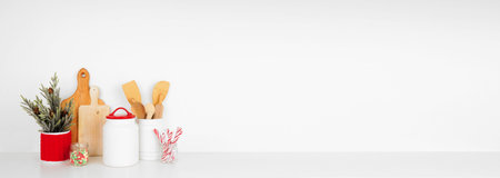 Christmas theme kitchenware, decor and sweets on a white shelf or counter. Banner against a white wall background with copy space.の写真素材