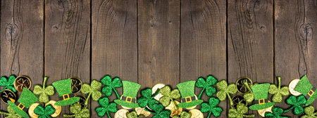 St Patricks Day bottom border against a dark wood banner background. Above view with gold coins,...