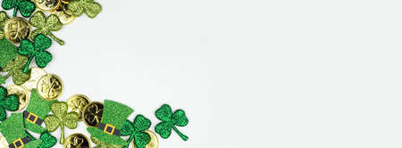 St Patricks Day corner border against a white banner background. Overhead view with gold coins, shamrocks and leprechaun hats. Copy space.の写真素材